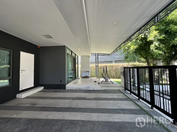 独立式住宅 出售在Bang Kapi, Bangkok - 车库旁落地窗与通向花园的黑色金属栅栏门。