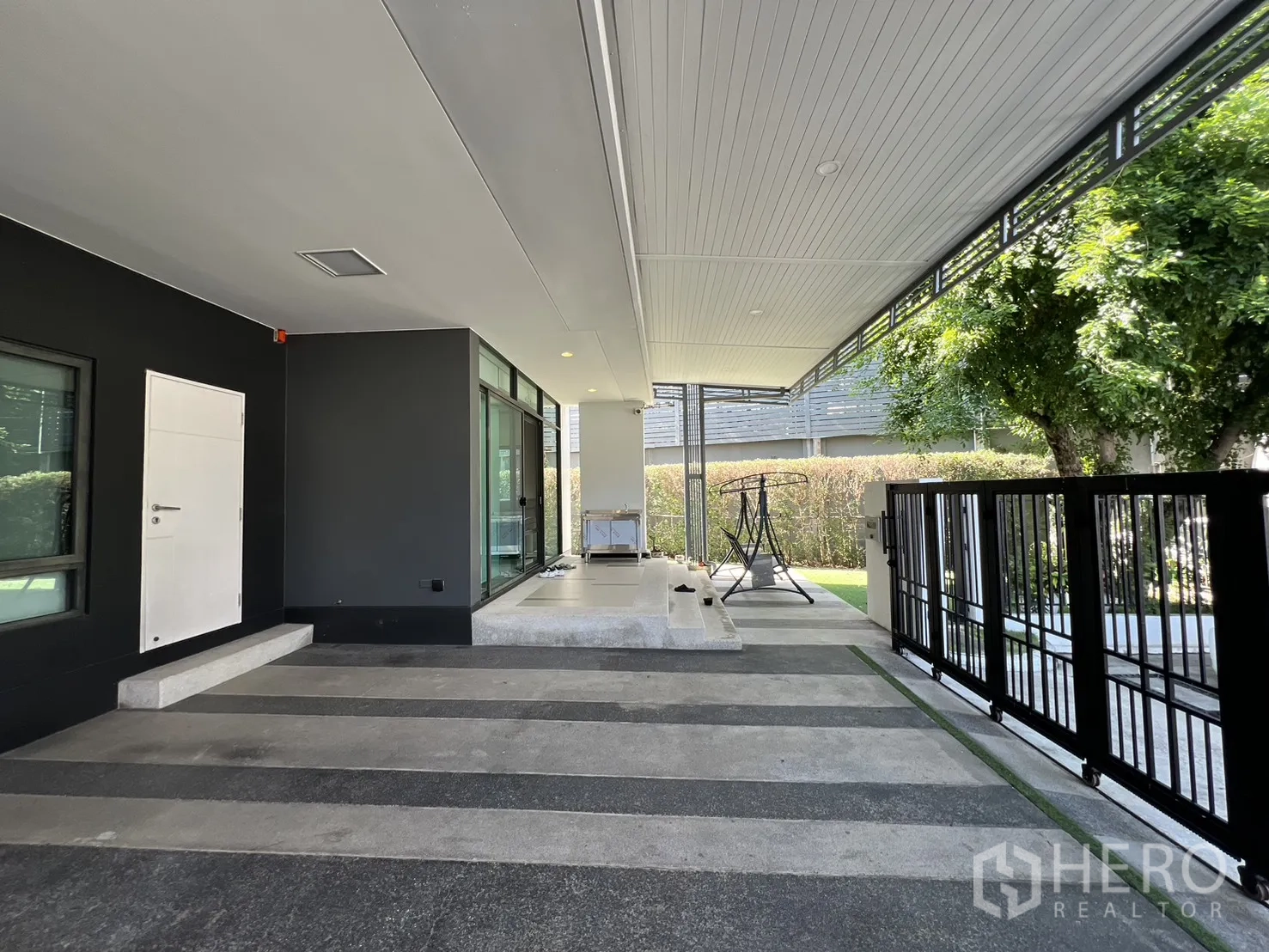 独立式住宅 出售在Bang Kapi, Bangkok - 车库旁落地窗与通向花园的黑色金属栅栏门。