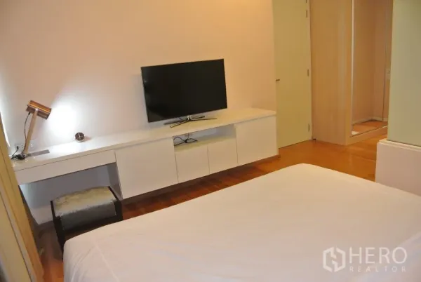 คอนโด ให้เช่าในWatthana, Bangkok - ผนังสื่อบันเทิงในห้องนอนใหญ่ พร้อมโต๊ะทำงานยาว ตู้วางทีวี และตู้เสื้อผ้าบานกระจก