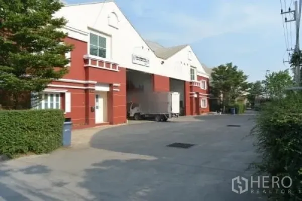 货栈 出租在Samut Sakhon - 红白色仓库外立面，设有大型卷闸装卸口。