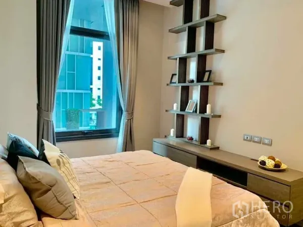 Condominium for rent in Watthana, Bangkok - Bright bedroom with large window, built-in shelves and city view through curtains.