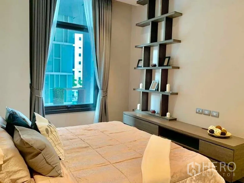 Condominium for rent in Watthana, Bangkok - Bright bedroom with large window, built-in shelves and city view through curtains.