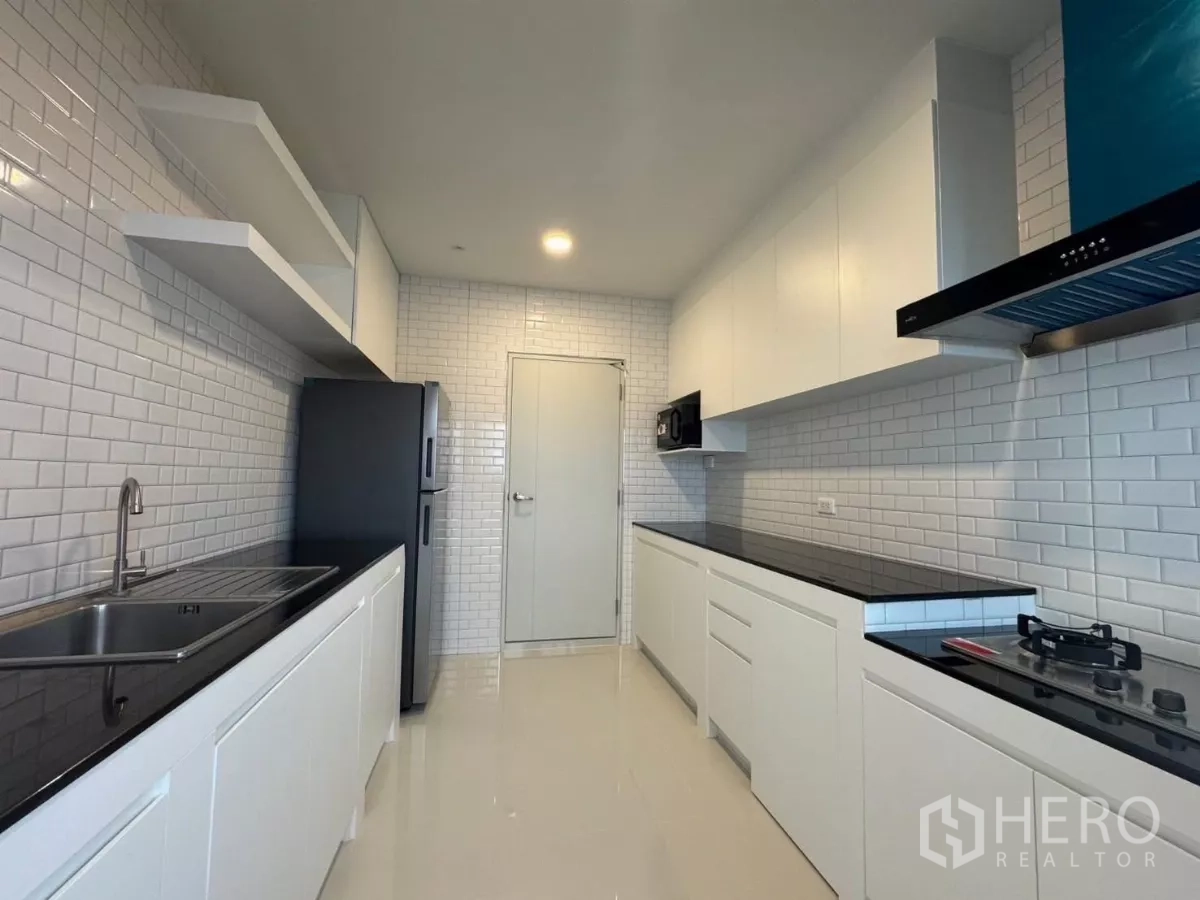 Detached House for rent or sale in Bang Phli, Samut Prakan - Sleek galley kitchen with white subway tiles, black countertops and appliances.