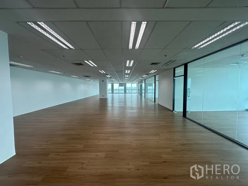 Office Space for rent - Long open workspace with LED strip lighting and a row of glass-walled rooms along the corridor.