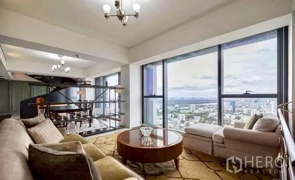 Condominium for rent in Sathon, Bangkok - Sitting area with built-in display shelves and wide windows framing city views and the spiral stair.
