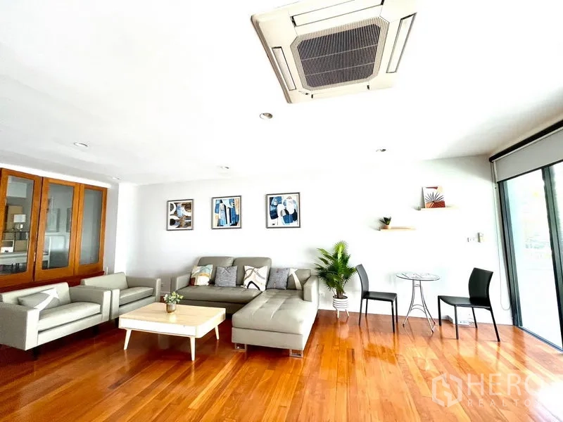 Townhouse for rent in Khlong Toei, Bangkok - Air-conditioned living area with large windows, sofa set and light decor.