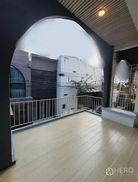 Townhouse for sale - Upper-floor balcony with arched opening and railing overlooking a quiet lane.