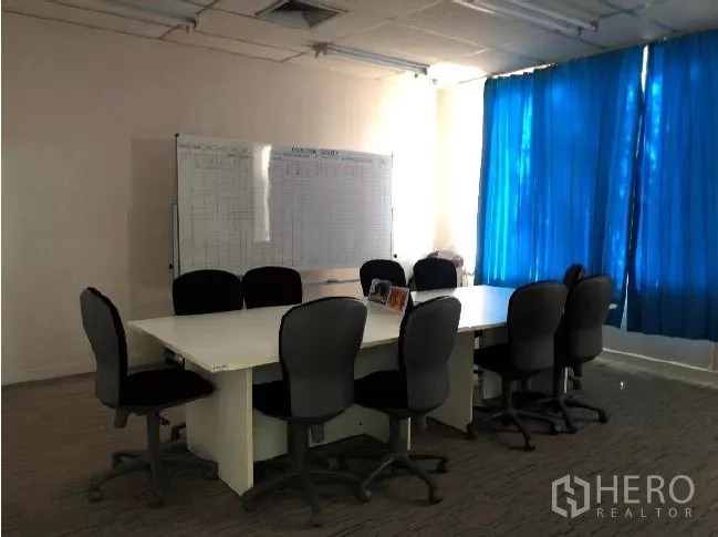 Factory for sale in Khlong Luang, Pathum Thani - Meeting room with conference table, office chairs, blue curtains and a whiteboard.