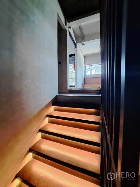 零售空间 出租在Watthana, Bangkok - 带LED灯的楼梯通往夹层，室内为混凝土墙面并有采光窗。