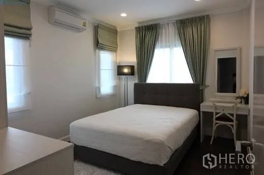Detached House for rent or sale in Prawet, Bangkok - Cozy secondary bedroom with double bed, vanity desk, green drapes, and air conditioning.