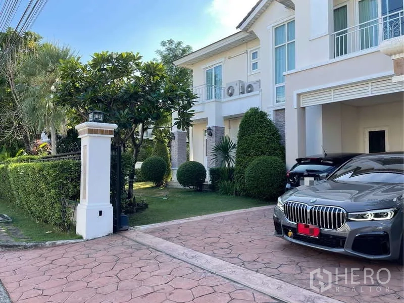 独立式住宅 出租在Prawet, Bangkok - 带大门的车道与车棚，草坪修剪整齐。