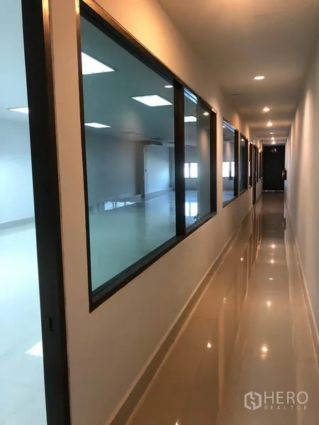 Warehouse for rent in Bang Sao Thong, Samut Prakan - Office corridor with glass partitions and polished tile floor.