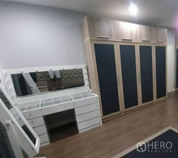 Detached House for sale in Pathum Thani - Bedroom corner with full-height wardrobes and a white dressing vanity with mirror.