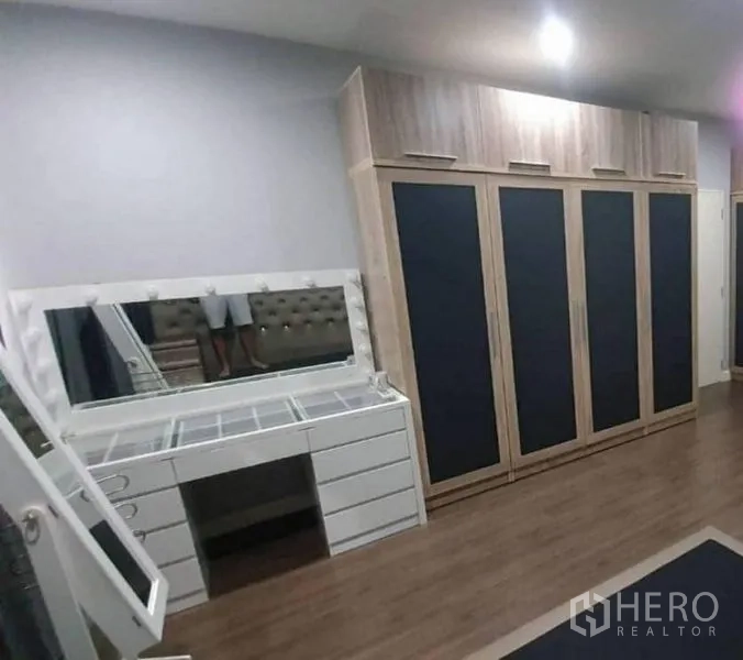 Detached House for sale in Pathum Thani - Bedroom corner with full-height wardrobes and a white dressing vanity with mirror.