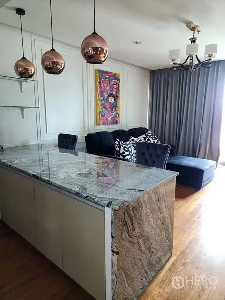 公寓 出租在Bang Rak, Bangkok - 石材吧台配铜色吊灯，对望带沙发与厚窗帘的起居区。