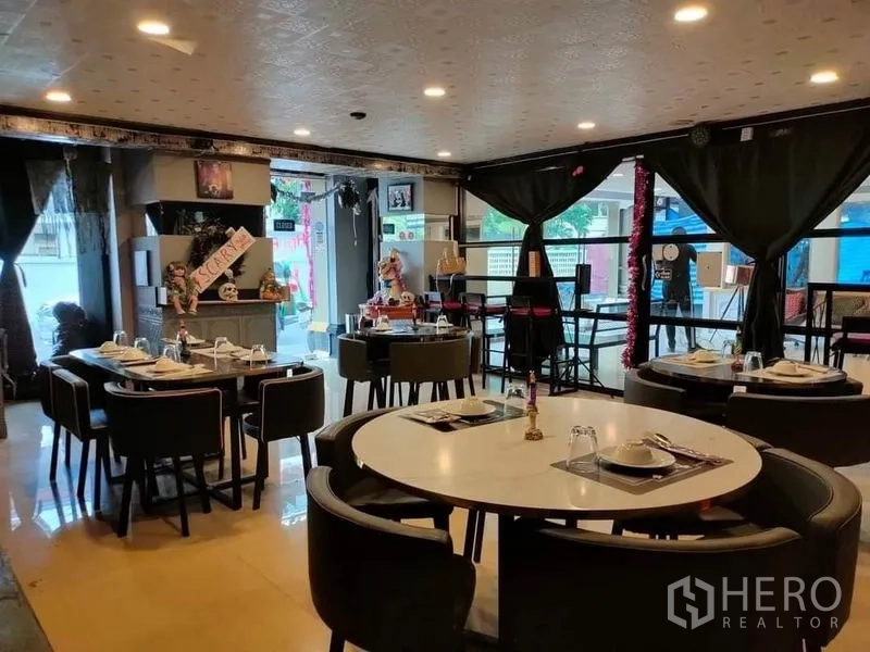 零售空间 出租在Watthana, Bangkok - 宽敞用餐区，圆桌与软包座椅，吧台和大窗户。