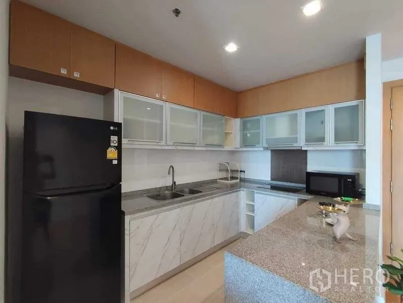 คอนโด ให้เช่าในKhlong Toei, Bangkok - ครัวพร้อมตู้เย็นสีดำ อ่างล้างจานคู่ และตู้เก็บของเหนือศีรษะ