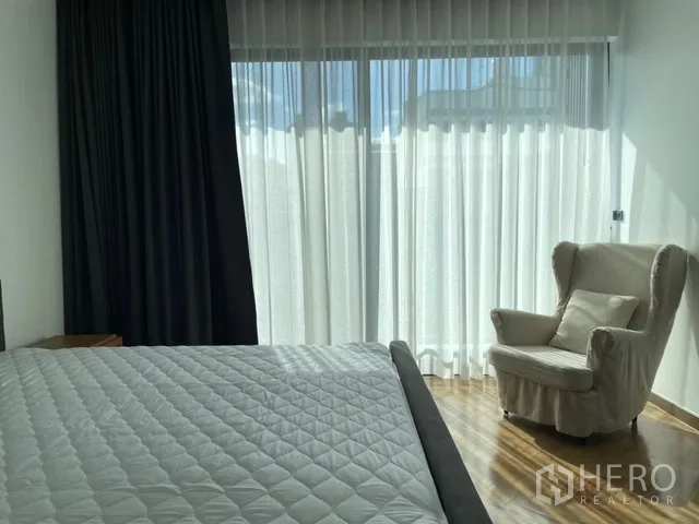 Detached House for rent in Watthana, Bangkok - Bedroom corner with wingback chair, bed, and light-filtering drapes.