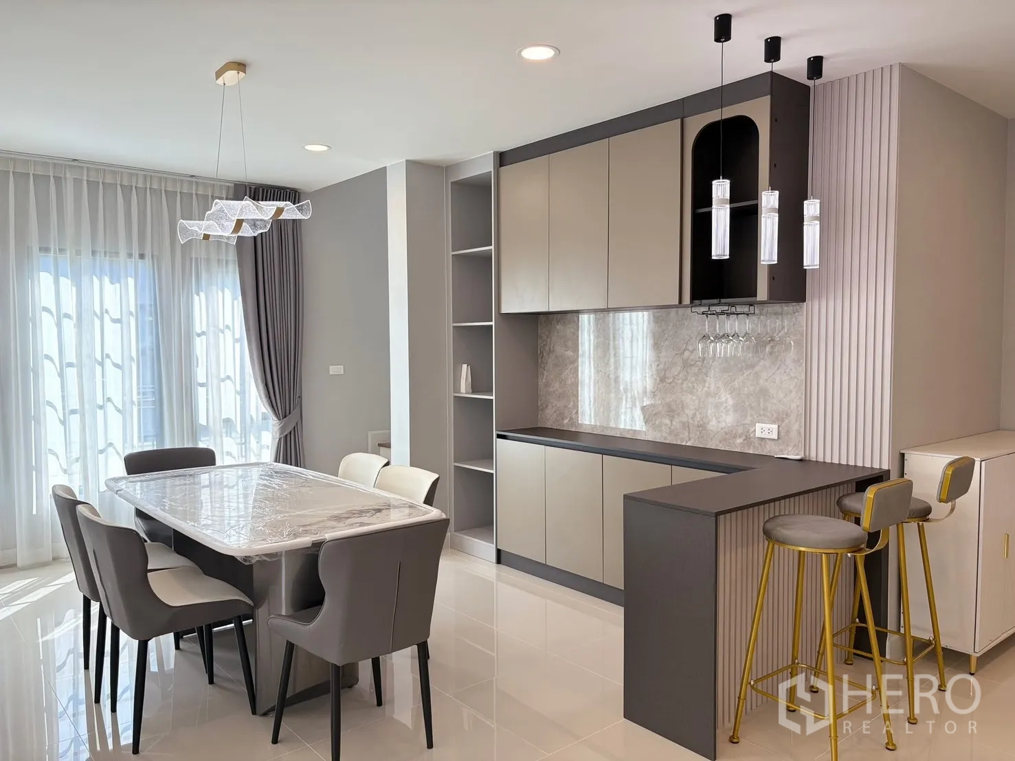 Detached House for rent in Bang Phli, Samut Prakan - Dining area with marble-top table for six, pendant lights, and modern pantry with breakfast bar and wine-glass rack.