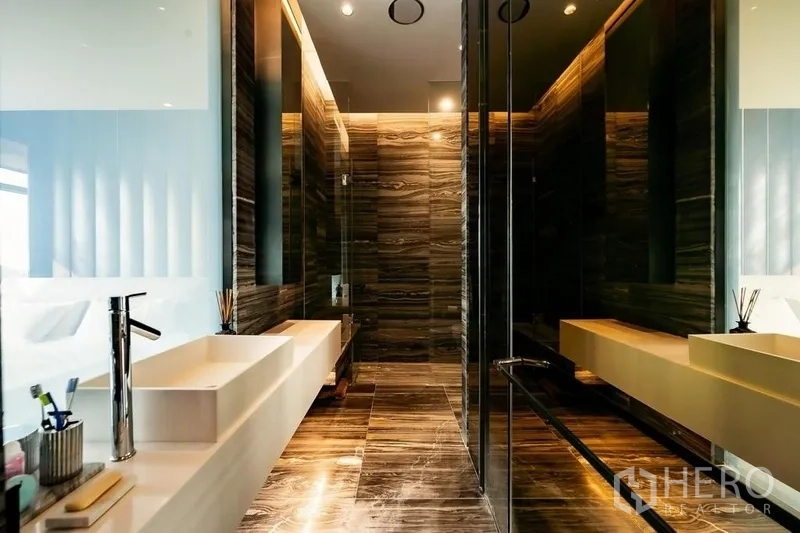 公寓 出售在Ratchathewi, Bangkok - 主卫配长形白色台盆、玻璃淋浴间与暖色石材墙地。