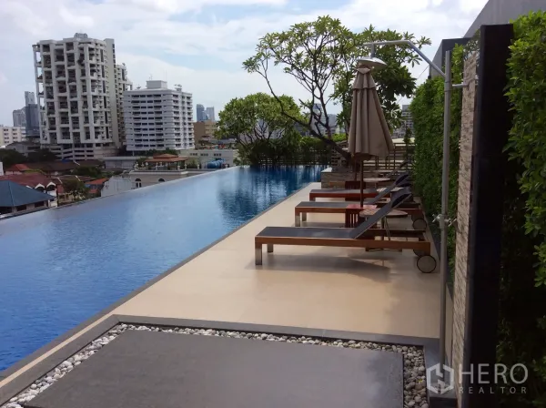 คอนโด ให้เช่าหรือขายในKhlong Toei, Bangkok - สระว่ายน้ำอินฟินิตี้บนดาดฟ้า พร้อมเตียงอาบแดด ร่ม และวิวเมืองกรุงเทพฯ ของคอนโดโมเดิร์น