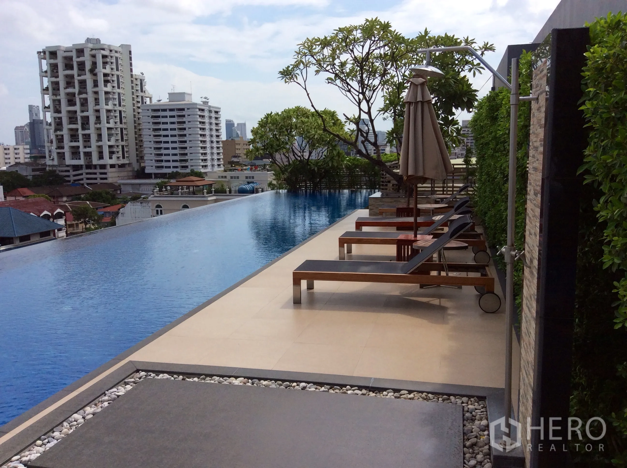 คอนโด ให้เช่าหรือขายในKhlong Toei, Bangkok - สระว่ายน้ำอินฟินิตี้บนดาดฟ้า พร้อมเตียงอาบแดด ร่ม และวิวเมืองกรุงเทพฯ ของคอนโดโมเดิร์น