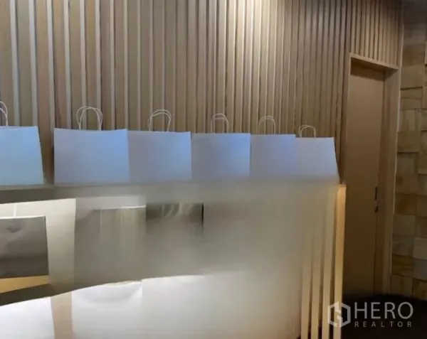 零售空间 出租在Watthana, Bangkok - 极简收银台，竖向木饰面墙与柔和灯光