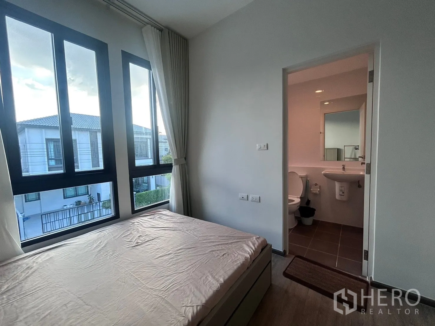 Semi-detached House for rent in Bang Phli, Samut Prakan - Cozy bedroom with large windows and en-suite bathroom visible through the doorway.