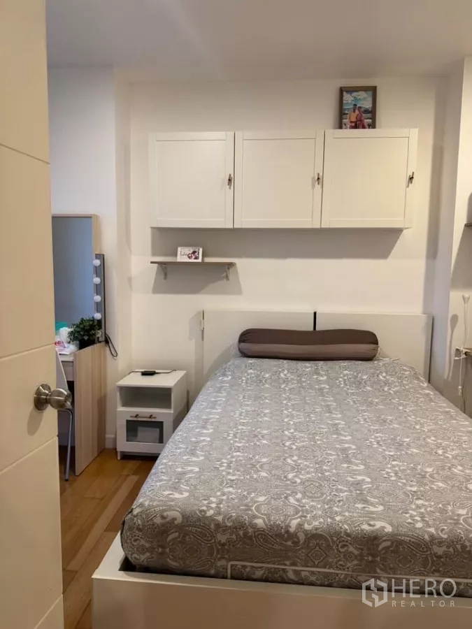 Condominium for rent in Watthana, Bangkok - Bedroom headboard wall with overhead cabinets, bedside tables and neutral bedding.