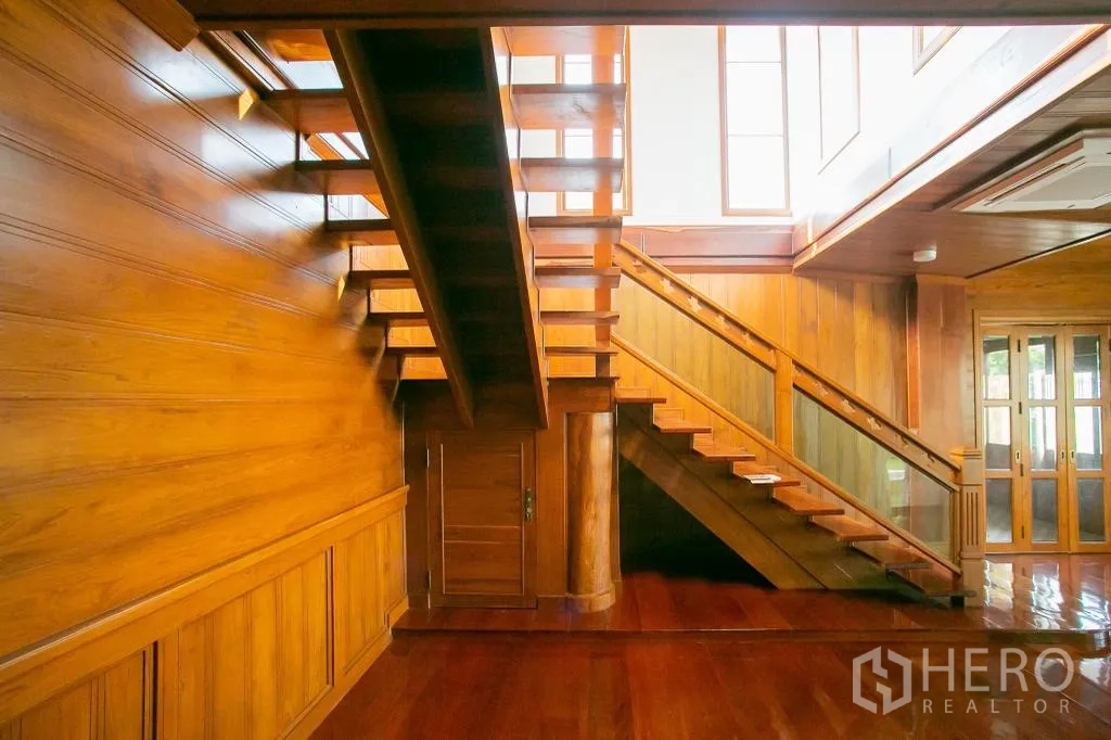 Detached House for rent or sale in Huai Khwang, Bangkok - Detail of wooden staircase and wall paneling with daylight from clerestory windows.