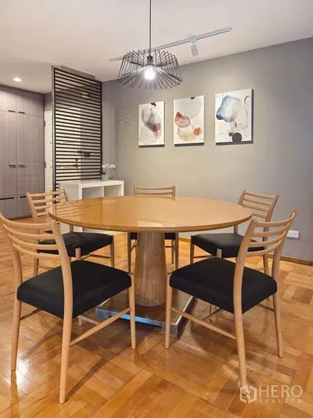 Condominium for rent in Yan Nawa, Bangkok - Dining area with round wooden table, four chairs and a pendant light.