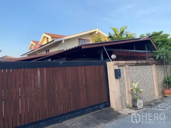 บ้าน ขายในWang Thonglang, Bangkok - มุมมองจากถนน เห็นรั้วสไลด์ไม้สูงและหน้าจั่วชั้นบนของตัวบ้าน