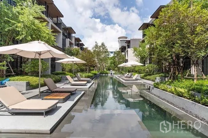 ทาวน์เฮาส์ ให้เช่าในKhlong Toei, Bangkok - สระว่ายน้ำส่วนกลางแบบยาว มีเตียงอาบแดดและร่ม ระหว่างอาคารโลว์ไรส์