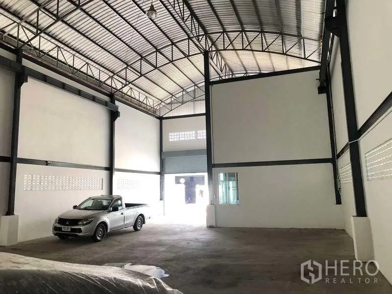 คลังสินค้า ให้เช่าในPak Kret, Nonthaburi - ภายในโกดังกว้าง มองไปยังประตูม้วนด้านหน้า พร้อมคานเหล็กและพื้นคอนกรีต