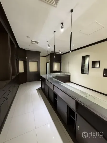 零售空间 出租在Sathon, Bangkok - 带玻璃台面的展示柜与内置橱柜沿窄厅排列。