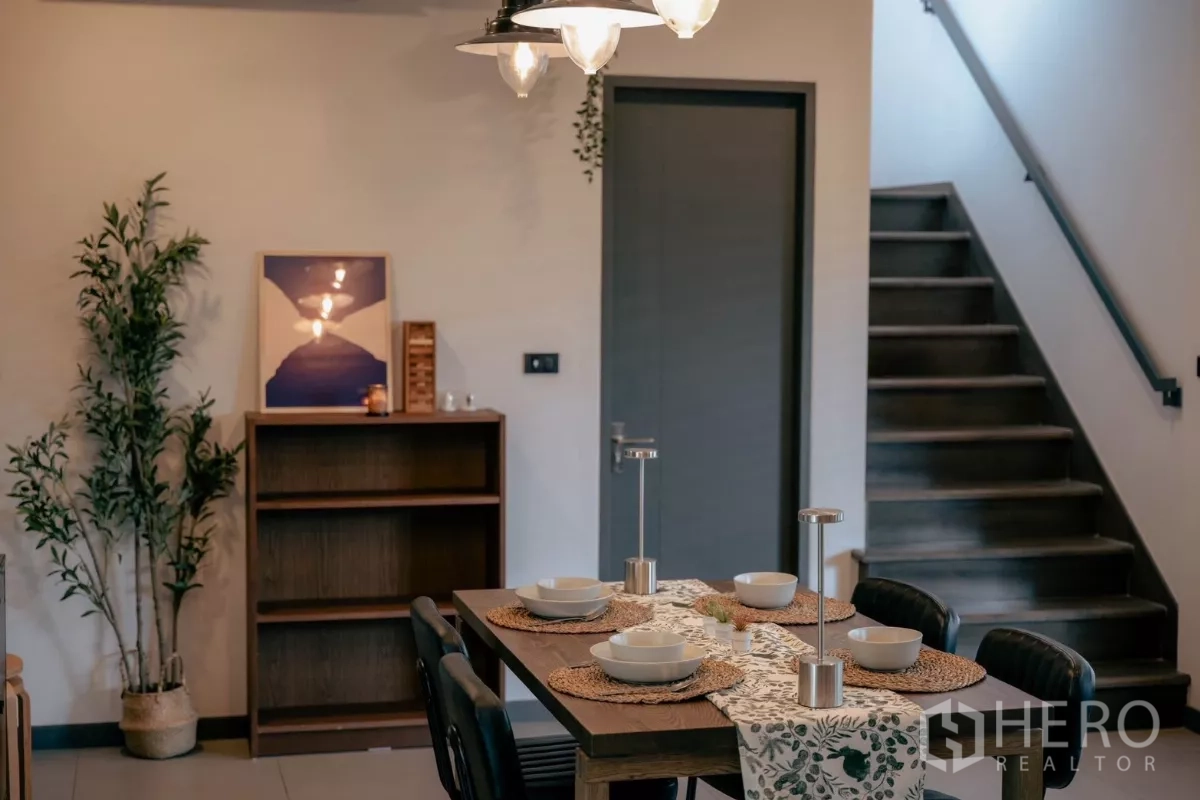独立式住宅 出租或出售在Bang Phli, Samut Prakan - 餐区设六人餐桌与楼梯及吊灯。