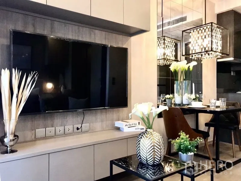 Condominium for rent in Watthana, Bangkok - TV feature wall facing sofa, mirrored dining area and decorative vases.