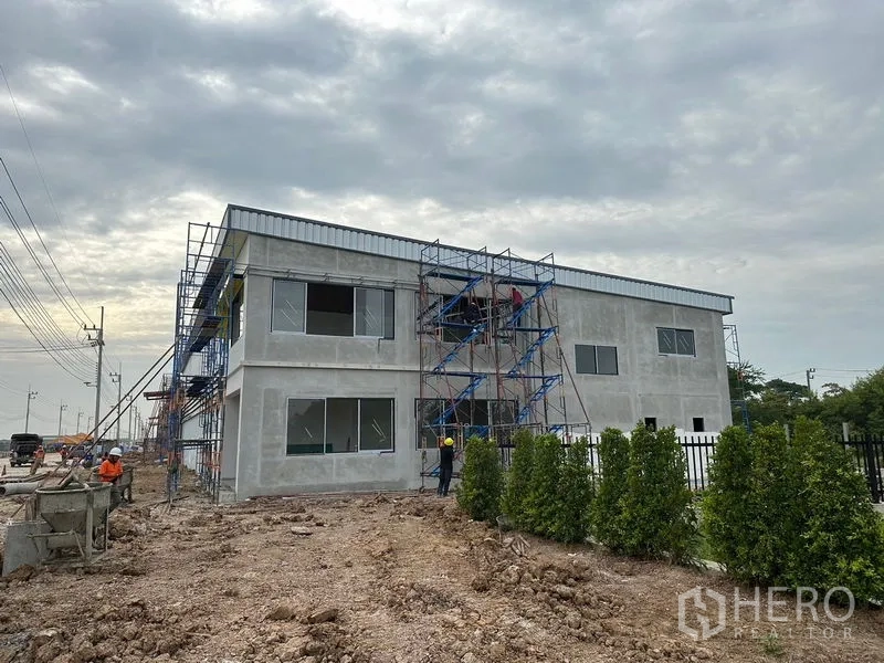 Warehouse for rent or sale in Lam Luk Ka, Pathum Thani - Two‑story office block under construction with scaffolding beside the warehouse site.