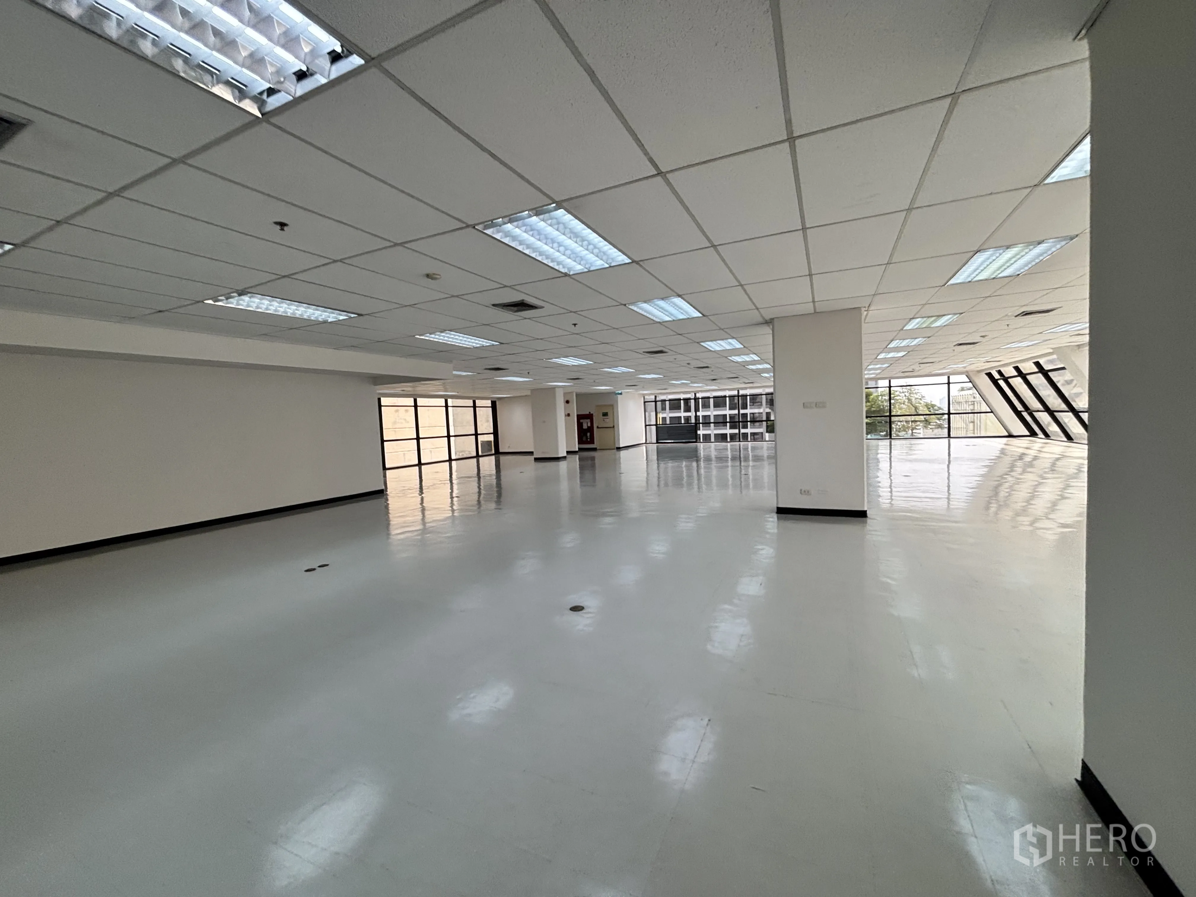 办公室 for rent in Ratchathewi, Bangkok - 开放工作区设有结构柱、浅灰地面，两端大窗引入自然采光。