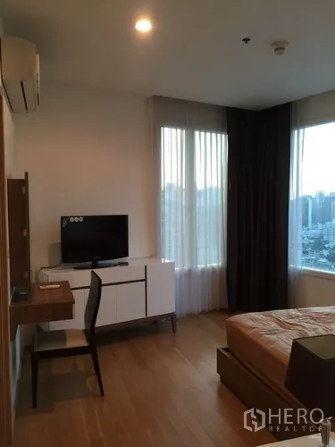 Condominium for rent in Watthana, Bangkok - Bedroom workspace with desk, TV console and a large window for natural light.