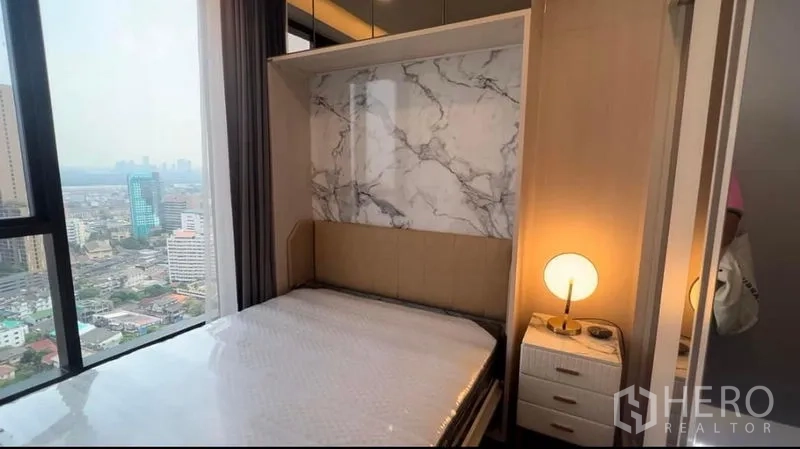 คอนโด ให้เช่าในKhlong Toei, Bangkok - ห้องนอนอบอุ่น ผนังลายหินอ่อน โต๊ะข้างเตียง และหน้าต่างวิวกรุงเทพฯ