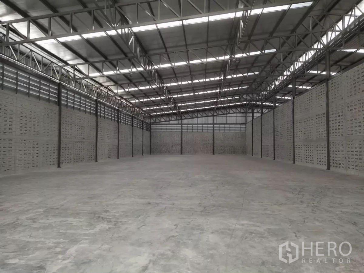 Warehouse for rent in Samut Prakan - Expansive warehouse interior featuring high steel truss roof, skylights and polished concrete floor.