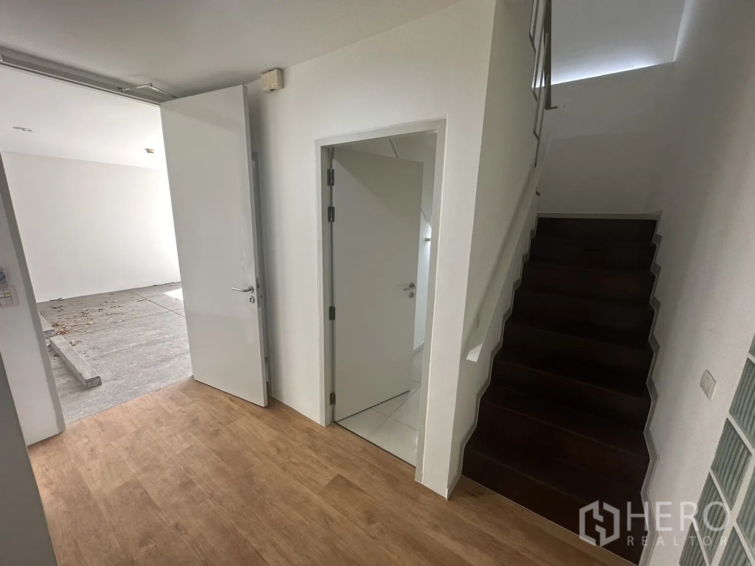 带办公室的家 出租在Phra Khanong, Bangkok - 一楼入口大厅，木地板、白色门与深色木楼梯。