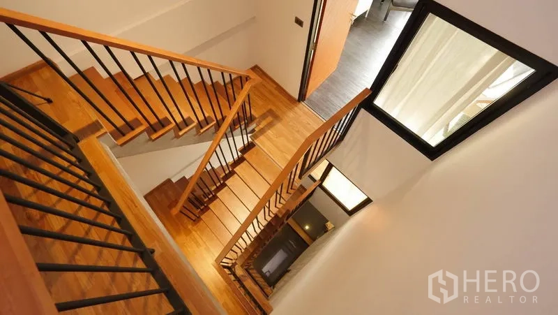 Townhouse for rent in Khlong Toei, Bangkok - Wooden staircase with black metal railings viewed from above.