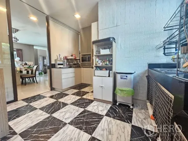 Detached House for sale in Prawet, Bangkok - Semi‑open kitchen with black and white chequered floor, built‑in cabinets and shelving.