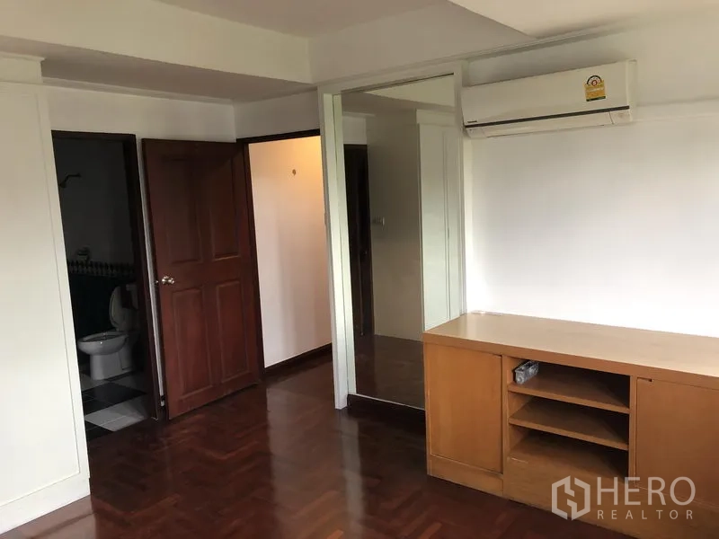 Townhouse for rent or sale in Watthana, Bangkok - Secondary bedroom with built-in desk, mirrored wardrobe and ensuite access.