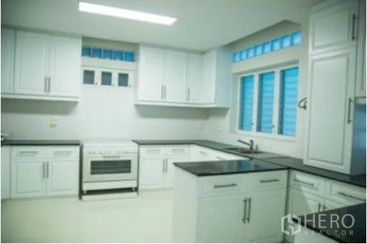 บ้าน ให้เช่าในKhlong Toei, Bangkok - ครัวสไตล์โมเดิร์น ตู้สีขาว ท็อปหินสีดำ เตาอบ และช่องหน้าต่างระบายอากาศ