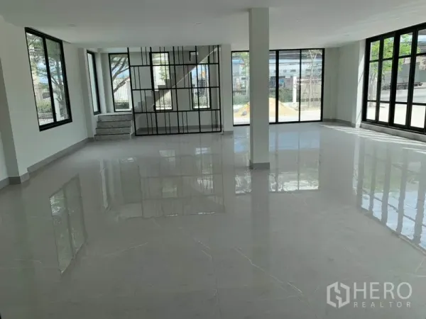 Warehouse for rent in Bang Phli, Samut Prakan - Ground-floor office area with a staircase and black metal partition, surrounded by wide windows for natural light.