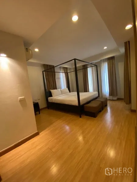 公寓 出租在Watthana, Bangkok - 主卧设四柱床、床尾凳、木地板与转角窗。