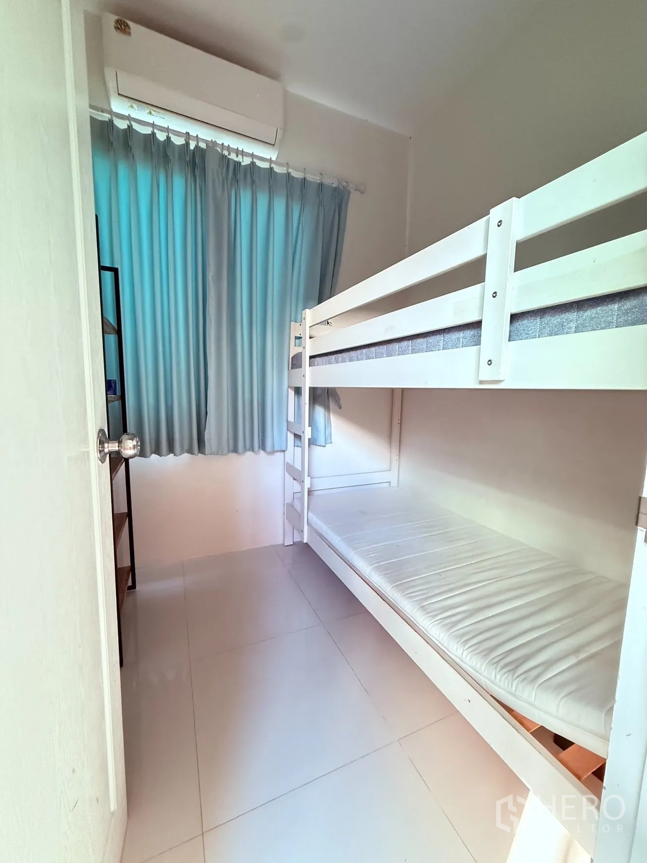 บ้านเดี่ยว for rent or sale in Prawet, Bangkok - ห้องขนาดกะทัดรัดพร้อมเตียงสองชั้น พื้นกระเบื้อง ผ้าม่าน และแอร์ผนัง.